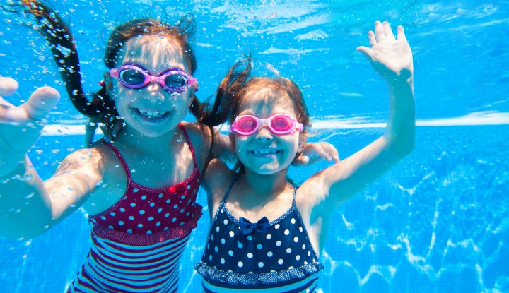 Two little girls deftly swim underwater in pool